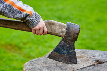 Child's hand holding an axe stuck in a wooden pencil case