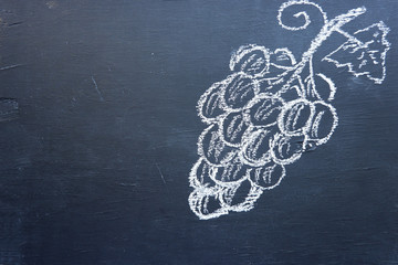 Grapes, drawing chalk on a black wooden board. Crafting a bunch of grapes. Empty place for text.