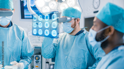 Surgeons Wearing Augmented Reality Glasses Perform State of the Art Augmented Reality Surgery in High Tech Hospital. Surgeon Looks at Brain Scans and Medical History of the Patient.