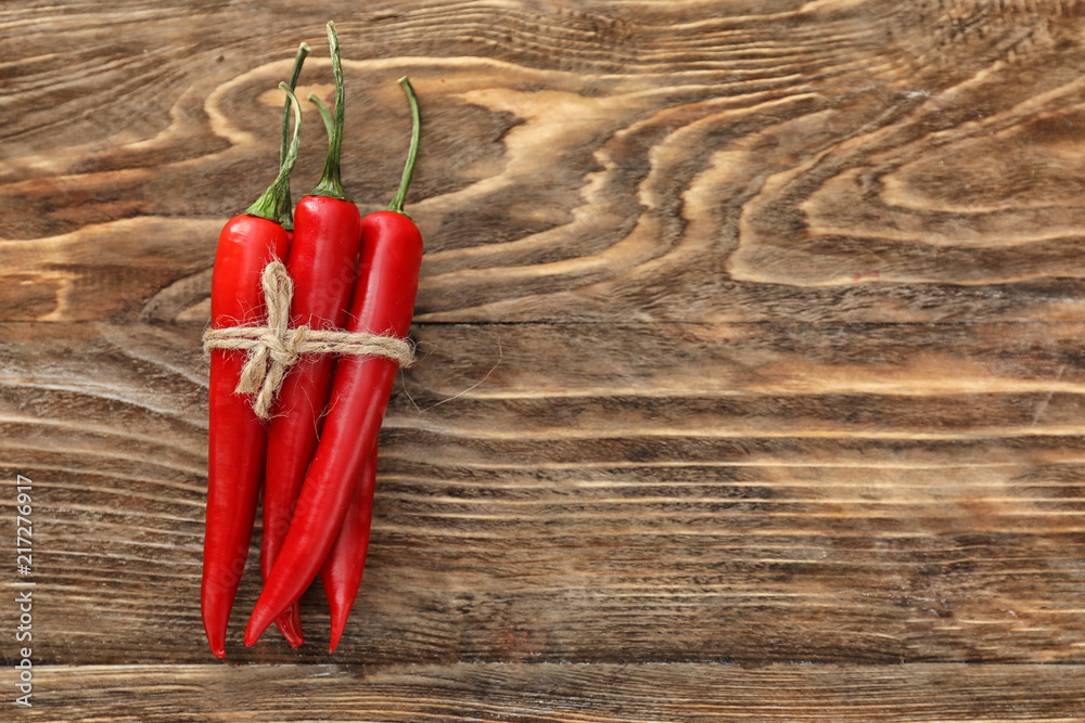 Tied fresh chili peppers on wooden background