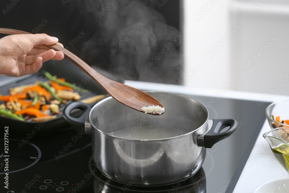 Woman boiling rice in kitchen