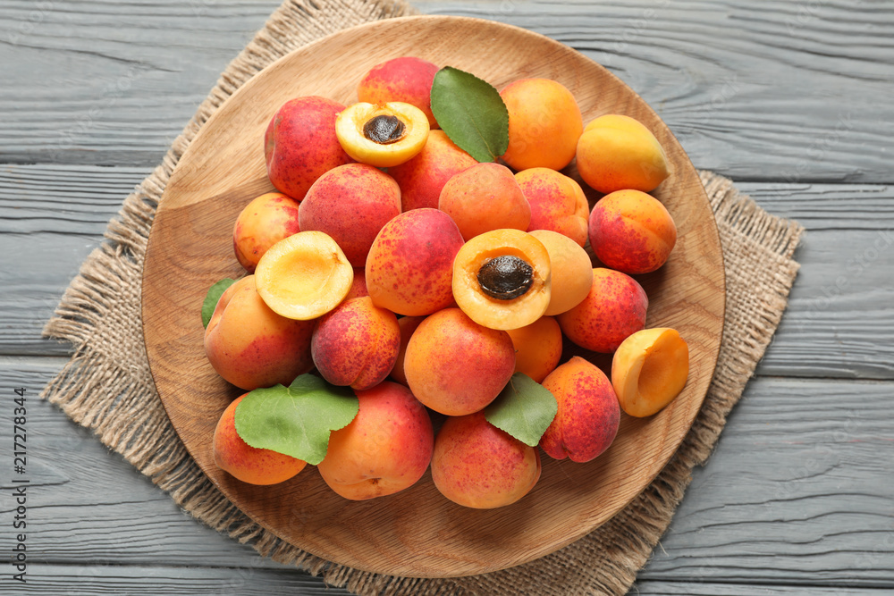 Plate with ripe sweet apricots on wooden background
