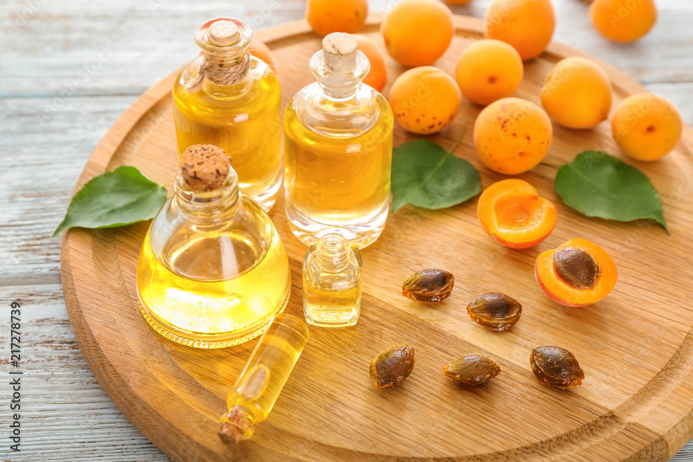 Bottles with apricot essential oil on wooden board