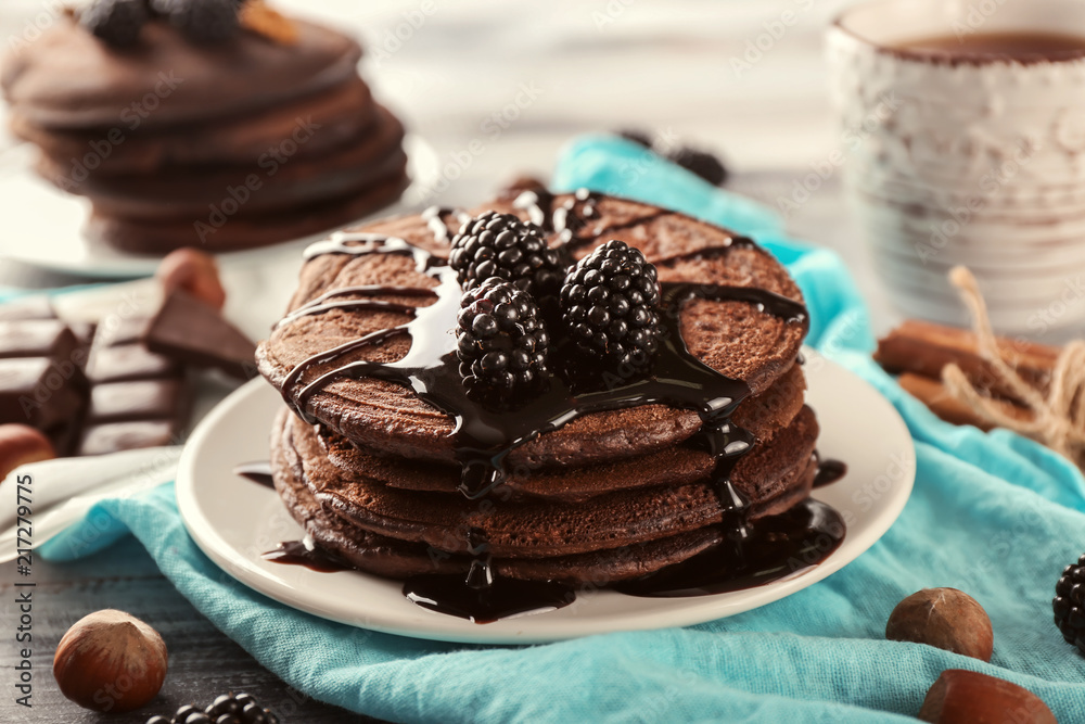 Plate with tasty chocolate pancakes on wooden table