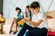 © LIGHTFIELD STUDIOS - young schoolboy writing in notebook while his classmates sitting behind