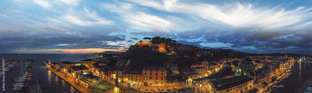 Panoramic aerial night view of Castiglione della Pescaia after sunset - obrazy, fototapety, plakaty 
