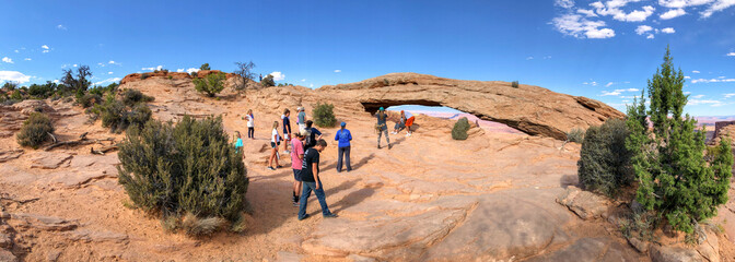 Canvas Print - CANYONLANDS, UT - JUNE 23, 2018: Tourists visit Mesa Arch, panoramic view. This is the main park attraction