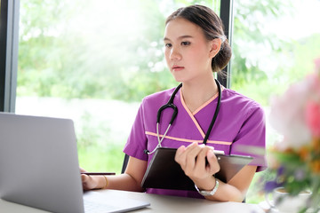 Asian woman doctor taking notes. Woman doctor working on workplace in hospital.