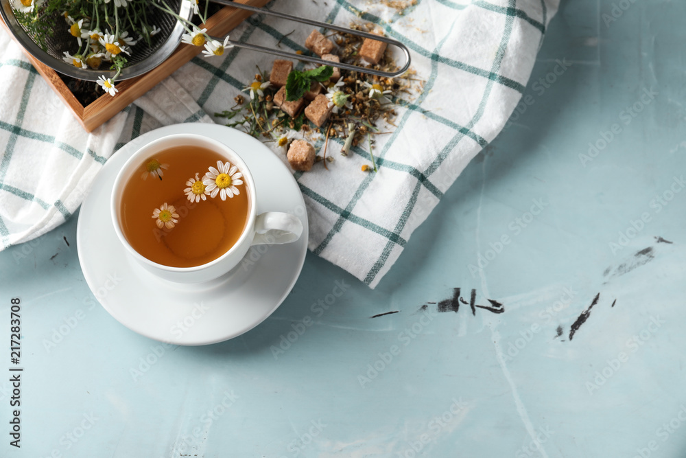 Cup of delicious camomile tea on light table