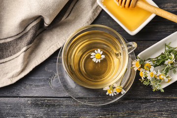 Cup of delicious camomile tea and honey on wooden table