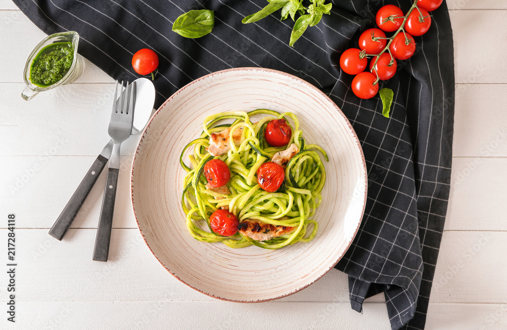 Plate with zucchini spaghetti, tomatoes and meat on light table