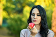 © dobok - young black hair woman eat red apple in a park in autumn