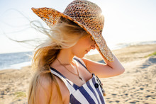 Side View Of Attractive Young Woman In Straw Hat On Sandy Beach In Riga, Latvia