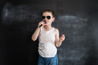 © cathyrina - Young boy's standing near blackboard singing in microphone. Rockstar. Creative design concept of future profession.