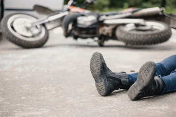 Irresponsible motorcyclist on the road and motorbike in the background after collision