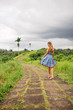 Beautiful young woman in blue vintage dress have fun at stone hill path in Asia. Girl travel and explore world. Long lonely road in mountains. Travel and adventure mockup. Romantic scene concept.