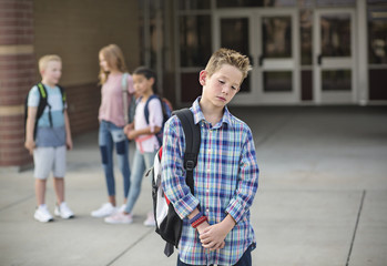 Sad boy feeling left out, teased and bullied by his classmates. Unhappy boy having problems fitting in with others at school