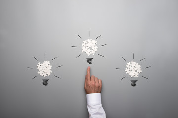 Wall Mural - Three light bulbs formed by scattered white puzzle pieces with hand of a businessman