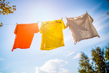 Photo Of Three T-shirts Hanging On Rope Against Blue Sky Background