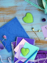 Decorative composition with a violet palette of hearts, flowers, artistic and stationery, seasonal still life on a light blue wooden background, top view. Concept of preparing for the holiday, backgro