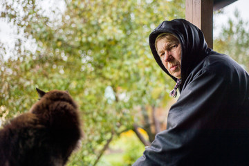 Mature woman on the porch of the house with a cat