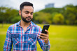 © Ranta Images - Portrait Of Young Handsome Indian Man In Park Using Mobile Phone