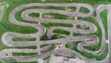Aerial top down view of motocross track showing the high-performance off-road motorcycles racing on the enclosed manmade dirt track with steep jumps and obstacles 4k high resolution quality footage
