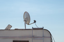 White Satellite Dish On A Caravan Against Blue Sky