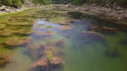 Wall Mural - aerial drone view flying low and backwards over a lake inside a narrow, tree lined canyon