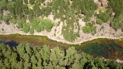 Wall Mural - aerial drone view flying sideways along a narrow canyon containing a lake