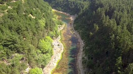 Wall Mural - aerial drone view descending into a narrow tree lined canyon containing a small lake at the bottom