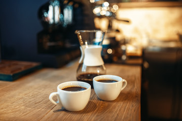 Two cups of fresh black coffee on wooden counter