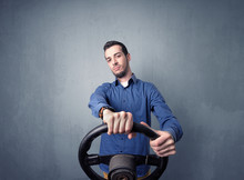Young Man Holding Black Steering Wheel On A Blueish Gray Background