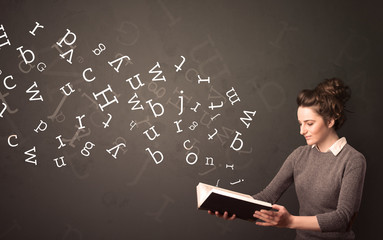 Wall Mural - Casual young woman holding book with white alphabet flying out of it