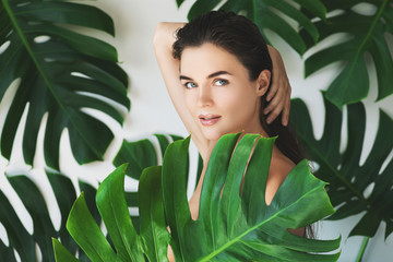 Wall Mural - portrait of young and beautiful woman with perfect smooth skin in tropical leaves