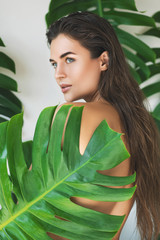 Wall Mural - portrait of young and beautiful woman with perfect smooth skin in tropical leaves