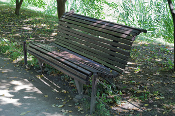 Old-fashioned wooden bench for rest in summer city park
