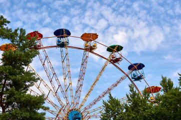 Wall Mural - Amusement park ferris wheel, blue sky with clouds, green trees