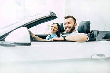 Auto showroom. Happy young couple chooses and buying a new car for the family in the dealership.