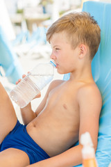 little boy drinking water on summer beach