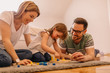© Nebojsa - Portrait of happy young family who is sitting of floor and playing with toys