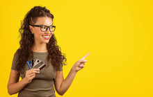 Smiling Woman With Credit Cards Pointing Away
