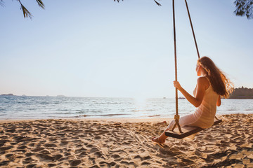 Wall Mural - dream and happiness concept, romantic beautiful carefree woman relaxing on the swing at sunset beach, summer holidays, vacation travel and relaxation, inspiring landscape