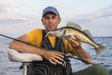 Wall Mural - Happy fisherman with zander fish trophy at the boat with fishing tackles