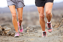 Runners Running Shoes On Trail Run. Ultra Running Athletes Legs Closeup On Desert Trail.