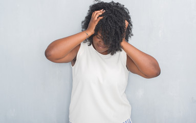 Wall Mural - Young african american woman over grey grunge wall suffering from headache desperate and stressed because pain and migraine. Hands on head.