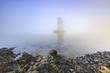 Pillar of a storm surge barrier in fog during sunset