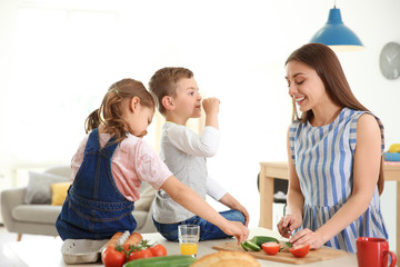 Poster - Young woman cooking breakfast for her children in kitchen. Happy family