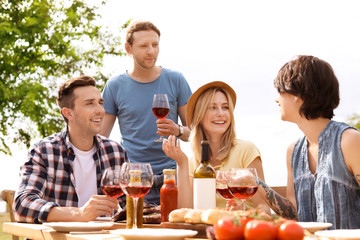 Poster - Young people with glasses of wine at table outdoors. Summer barbecue