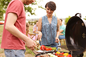 Canvas Print - Young people having barbecue with modern grill outdoors